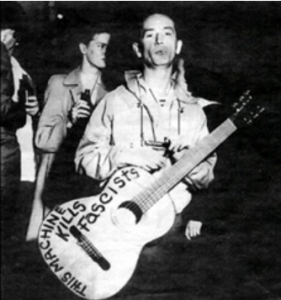 Photo by Karen Apricot, Woody Guthrie, This Machine Kills Fascists written on body of his guitar