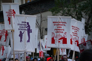 Outdoor rally with banners saying, "Stop Starving Our Schools" and "Educators, Students, and Parents United"