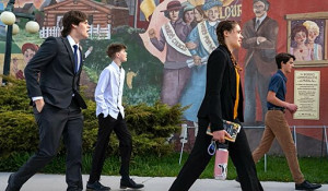 Photo of four young plaintiffs walking in front of a progressive-era mural
