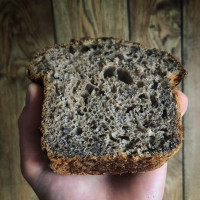 A loaf of barley bread held by a hand.