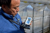 Takeshi Yamakawa of Tokyo Shimbun shows that the air dose level inside a greenhouse in Iitate Village is 0.433 μSv/hour, nearly twice as high as the government standard for outdoors of 0.23 μSv/hour.  (Photo courtesy of U. G. Kaneko)